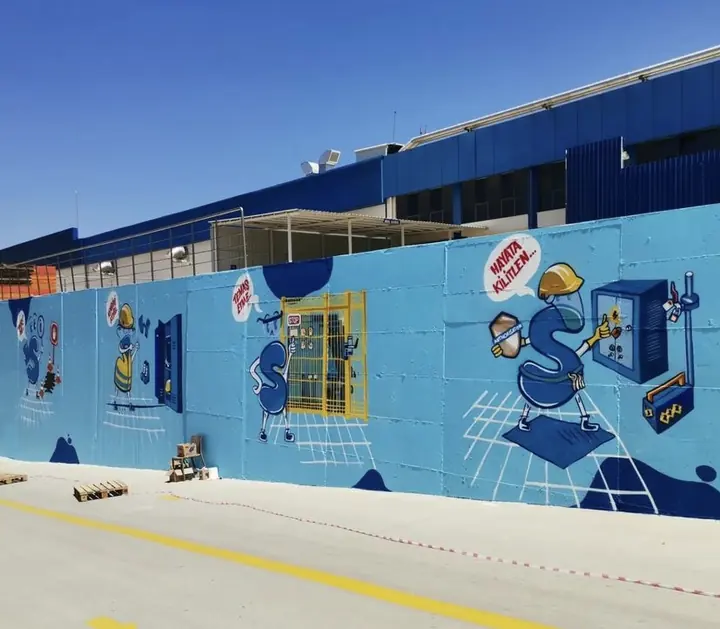Mavi fabrika duvarı boyunca uzanan mural